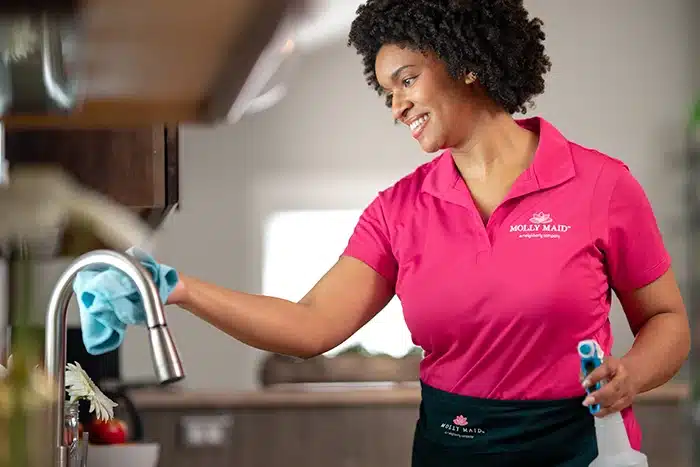 A Molly Maid professional wiping a sink during an occasional cleaning appointment.